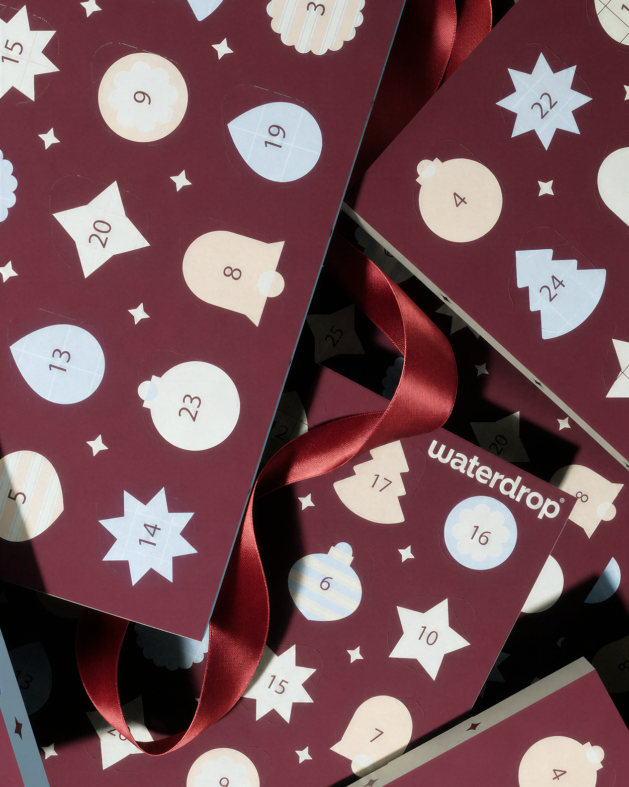Advent calendar with numbered doors on maroon panels and red ribbons.